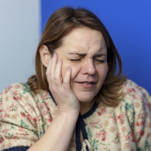 Woman holding her jaw and toothbrush