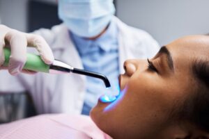 Dentist applying UV light to woman's tooth-colored filling
